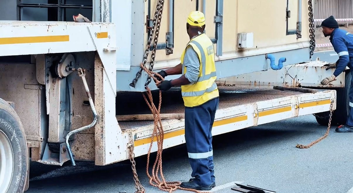 Crew loading a cabin onto a trailer
